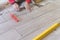 Man installing rectangular shaped floor tiles in kitchen. Applying adhesive before installation and verifying afterwards