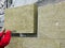 A man installs a layer of thermal insulation on the wall of the stairs outside - using mineral wool panels.