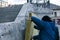 A man installs a layer of thermal insulation on the wall of the stairs outside - using mineral wool panels.