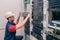 A man installs new equipment in a modern data center. An engineer in a white helmet mounts a stack of switches in a rack. The