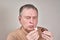 A man instills medicine into his ear with a small pipette from a pharmacy bottle