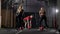 Man instructor is demonstrating exercise with balls for two slim women in gymnastic hall, personal training