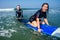 Man instructor demonstrating how to stand up on surfboard to indian woman in surf class in Goa sea