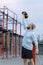 A man with an interesting braid hairstyle in a blue hoodie works out early in the morning on the street and lifts a kettlebell