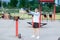 A man with an interesting braid hairstyle in a blue hoodie works out early in the morning on the street and lifts a kettlebell