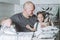 Man ironing bed linen with little daughter on his knees. Father is engaged in household chores.