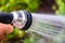 A man irrigates his garden with a pressure hose spraying water on the plants