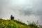Man isolated feeling the serene nature at hill top with amazing cloud layers in foreground