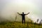 Man isolated feeling the serene nature at hill top with amazing cloud layers in foreground