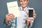 Man isolated on gray wall tourism concept standing holding dictionary and phone close-up smiling confused