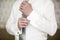 Man in ivory shirt and tie puts on cufflink.