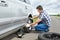 Man with jack changing a spare tire of car