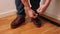 Man in jeans putting on and tying dark brown shoes. People backgrounds