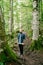 Man in jeans and a shirt stands on a hiking trail on a slope in a park