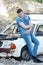 Man in jeans, sitting on an old damaged car