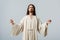 Man in jesus robe with outstretched hands isolated on grey