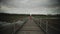 Man jogger in orange sweatshirt runs across wood bridge in nature in Scandinavia in in fall. Athlete runs across