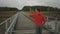 Man jogger in orange sweatshirt runs across wood bridge in nature in Scandinavia in in fall. Athlete runs across