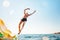 Man jumping backwards somersault into the sea. Happy beach vacation concept image