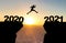 Man jumps over abyss in front of sunset with the inscription 2020 and 2021