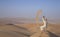 Man in kandura in a desert, throwing sand