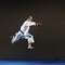 A man in karategi strikes with a hand in a jump