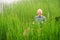 Man in kayak paddling through coastal grass