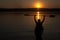 Man on kayak rising hands with the paddle on the lake on a summer evening