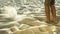 Man in khaki shorts sieving sand with feet