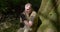 A man in a khaki uniform is resting in the forest under a tree