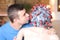 Man kissing person with coronavirus rubber mask