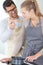 Man in kitchen letting woman taste with spoon