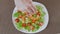 A man in the kitchen preparing a salad of avocado, zucchini and cherry tomatoes and shrimp. Closeup of fingers