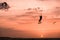 Man kitesurfer athlete jumping at sunset, silhouette at dusk man doing kitesurfing jump