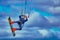 A man kitesurfer makes a jump against the background of a cloudy blue-white sky