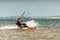 Man kitesurfer rides kite splashing on Bugaz firth at Black Sea coast on sunny day having fun and showing sign