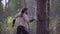 A man with a knife in his hands running through the woods among the trees. The camera leads him from left to right. That`s a nice