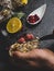 A man with a knife opens a fresh oyster. Dark stone background with lemon, ice, berries, selective focus