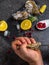 A man with a knife opens a fresh oyster. Dark stone background with lemon, ice, berries, selective focus