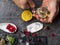 A man with a knife opens a fresh oyster. Dark stone background with lemon, ice, berries, selective focus