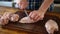 The man knives a raw chicken into pieces on a cutting board