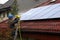 A man on a ladder cleaning solar panels