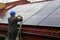 A man on a ladder cleaning solar panels