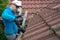 Man on ladder cleans gutter on the roof