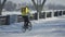 Man with large bag in helmet rides bicycle along snowy street and delivers food or parcels. Fast courier delivery in