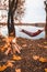 man laying dawn in hammock at autumn lake view. bonfire. camping concept