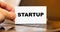 A man lays down a business card on the table with the word - Startup