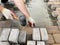 Man lays paving stones on the sand, restoring a patch of damaged pavement in the yard of a house