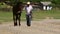 Man leading his horse down a country road