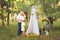 A man leads a woman with closed eyes to a picnic site with a white cloth curtain tent. Guitar and bicycle with